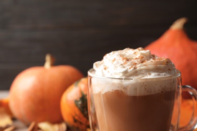 Photo of Glass cup with tasty pumpkin spice latte on table, closeup