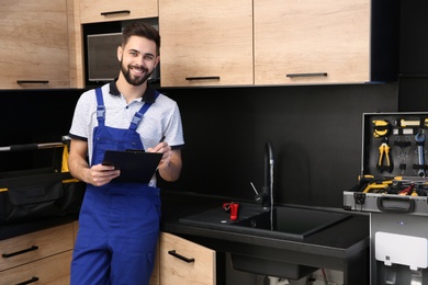 Photo of Male plumber with clipboard near kitchen sink. Repair service