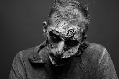 Photo of Scary zombie on dark background, black and white effect. Halloween monster