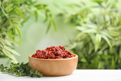 Photo of Bowl of dried goji berries on table against blurred background. Space for text