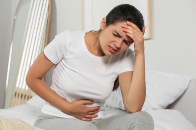 Photo of Young woman suffering from cystitis on bed at home