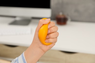Photo of Woman squeezing antistress ball in office, closeup