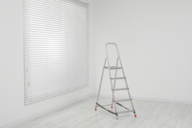 Photo of Metallic folding ladder indoors, space for text