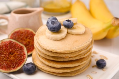 Photo of Tasty oatmeal pancakes with fruits on plate, closeup