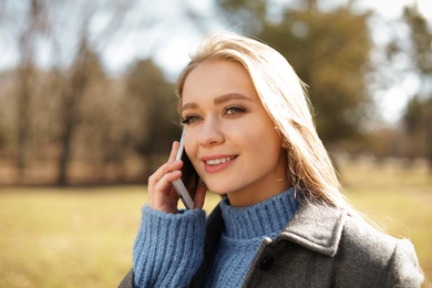 Photo of Portrait of beautiful young woman talking on phone in city park