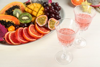 Photo of Delicious exotic fruits and wine on white wooden table