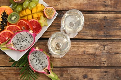 Photo of Delicious exotic fruits and wine on wooden table, flat lay