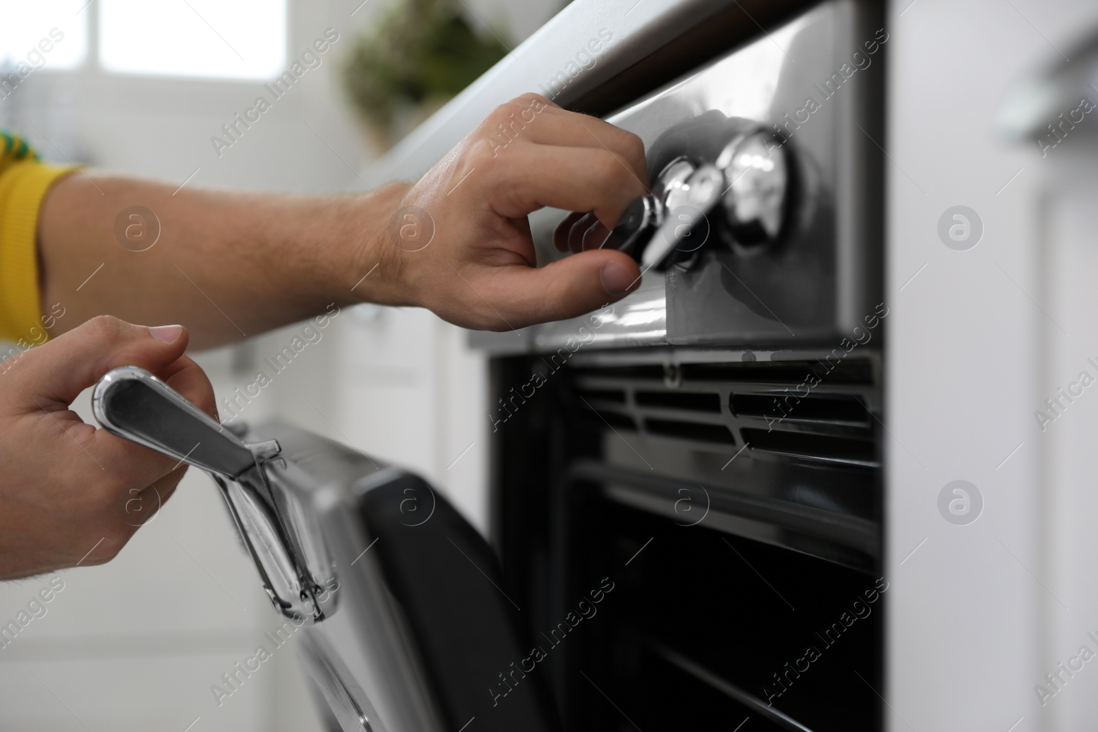 Photo of Man using modern oven in kitchen, closeup