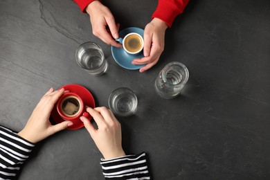 Photo of Women having coffee break at dark textured table, top view