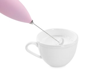 Photo of Whisking milk in cup with mini mixer (frother wand) isolated on white
