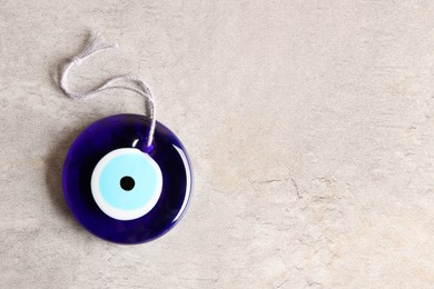 Photo of Evil eye amulet on light grey table, top view. Space for text