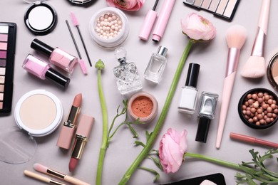 Photo of Flat lay composition with different makeup products and beautiful spring flowers on gray background