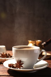Photo of Cup of aromatic hot coffee with anise stars on wooden table