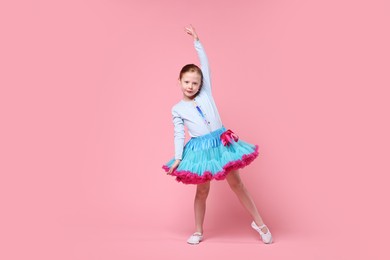Photo of Cute little girl dancing on pink background