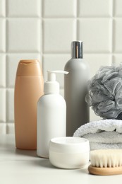 Photo of Different bath accessories and personal care products on white table near tiled wall