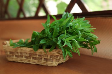Photo of Beautiful green mint in wicker basket on wooden table