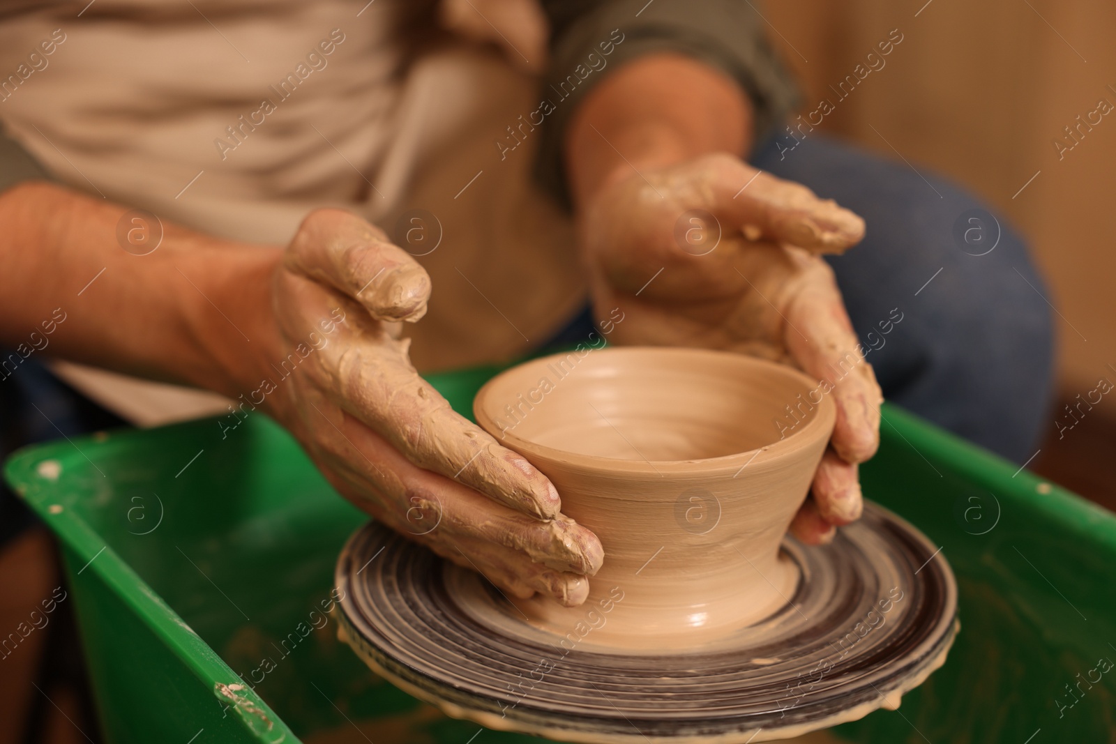 Photo of Clay crafting. Man making bowl on potter's wheel, closeup