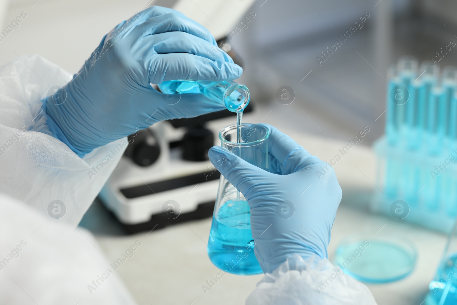 Scientist working with flasks in laboratory, closeup Photo of Scientist working with flasks in laboratory, closeup