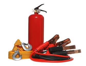 Photo of Red fire extinguisher, towing strap and battery jumper cables on white background. Car safety