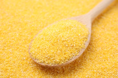 Photo of Wooden spoon on raw corn grits, closeup