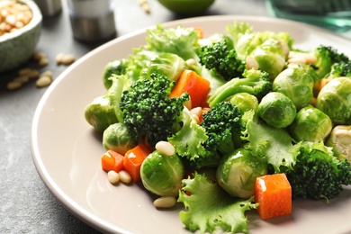 Photo of Plate of salad with Brussels sprouts and broccoli on table, closeup