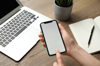 Photo of MYKOLAIV, UKRAINE - JULY 8, 2020: Woman using Iphone 11 Pro Max with blank screen at workplace, closeup