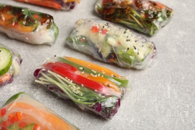 Photo of Many different delicious rolls wrapped in rice paper on grey table, closeup