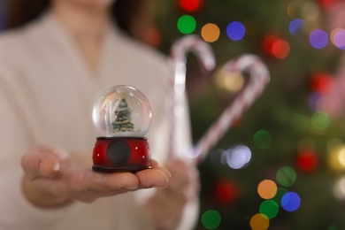 Photo of Woman holding snow globe on blurred background, closeup. Space for text