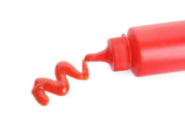 Photo of Squeezing tasty ketchup from bottle isolated on white, top view. Tomato sauce