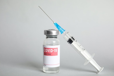 Photo of Vial with coronavirus vaccine and syringe on light background