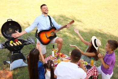 Photo of Man playing guitar for friends at picnic in park