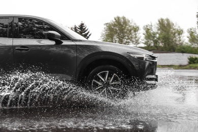 Photo of Modern car driving outdoors on rainy day
