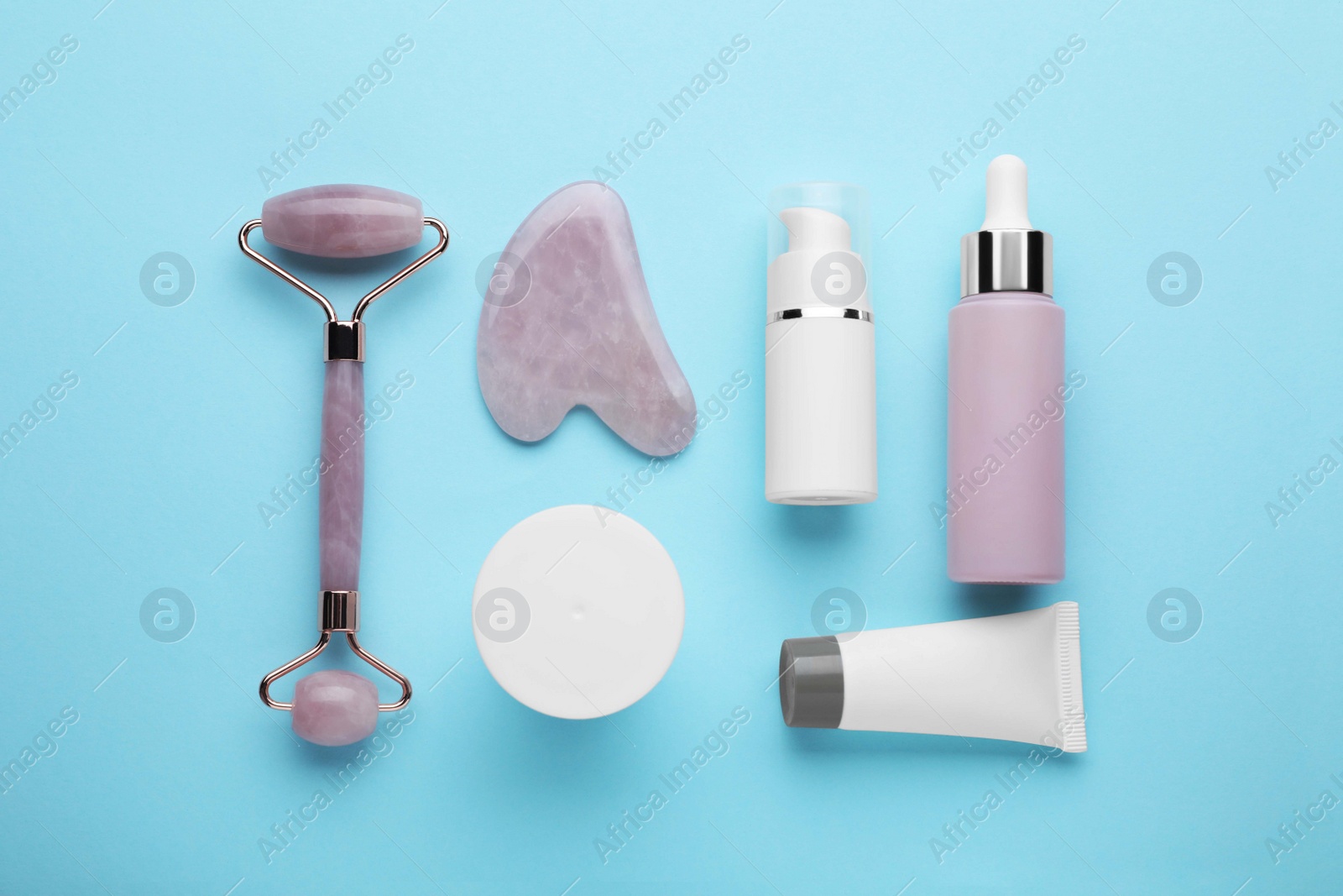Photo of Flat lay composition with gua sha tool and, face roller and skin care products on light blue background