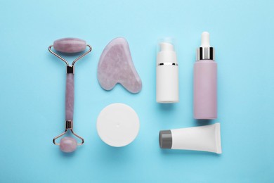 Photo of Flat lay composition with gua sha tool and, face roller and skin care products on light blue background
