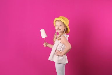Photo of Cute little girl with cotton candy on color background