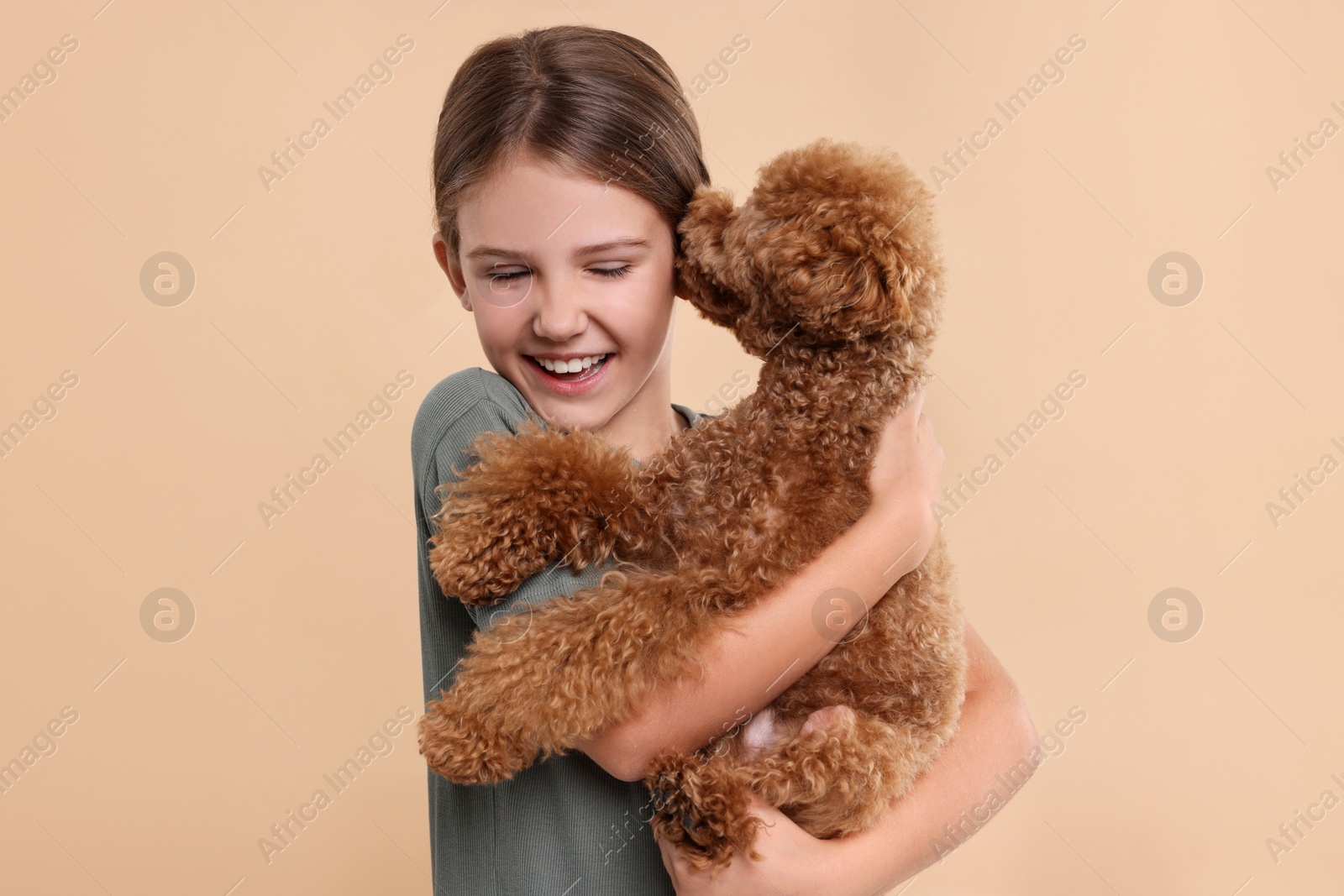 Photo of Little child with cute puppy on beige background. Lovely pet