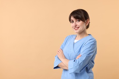 Photo of Portrait of smiling medical assistant with crossed arms on beige background. Space for text