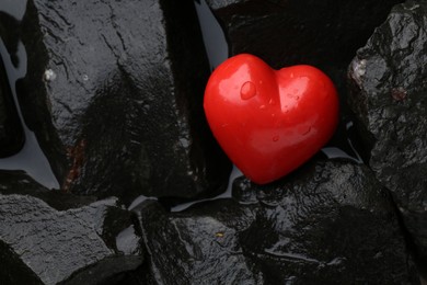 Photo of Red decorative heart on stones and water, top view. Space for text
