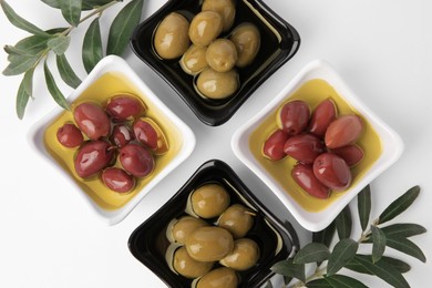 Photo of Bowls with different ripe olives and leaves on white background, flat lay