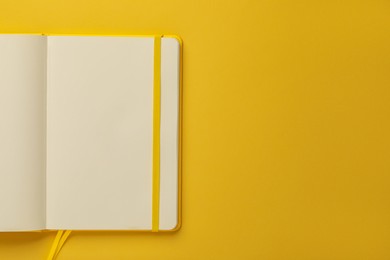 Photo of Blank notebook on yellow background, top view. Space for text