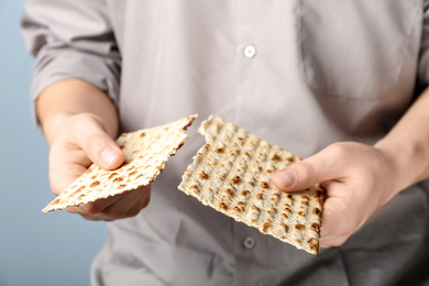 Photo of Man with Matzo on grey background, closeup. Pesach (Passover) celebration