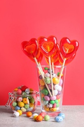 Photo of Delicious heart shaped lollipops and dragees on table