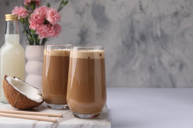 Delicious coffee with coconut syrup on white table, space for text