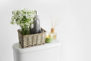 Decor elements on toilet tank near white wall, space for text. Bathroom interior