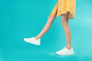 Photo of Woman in stylish sport shoes on light blue background