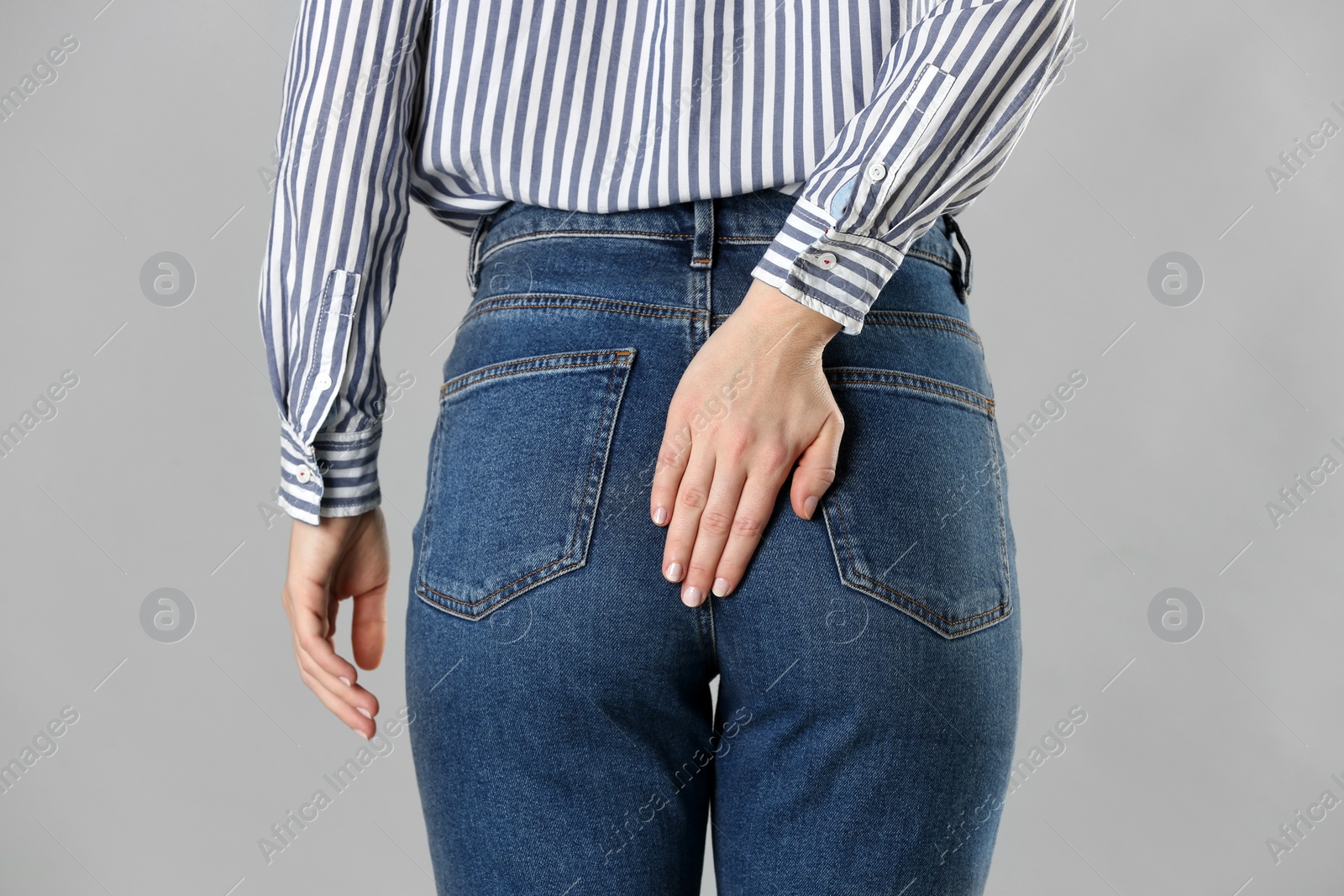 Photo of Woman suffering from hemorrhoid on light grey background, closeup