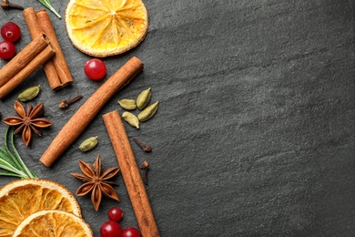 Different mulled wine ingredients on black slate table, flat lay. Space for text