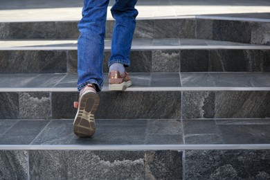 Photo of Woman walking up stylish stone stairs outdoors, closeup