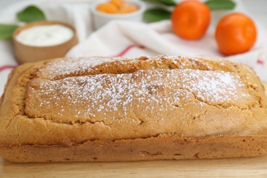 Delicious homemade yogurt cake with powdered sugar on wooden table, closeup