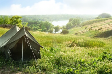 Photo of Camping tent in green field on sunny day. Space for text